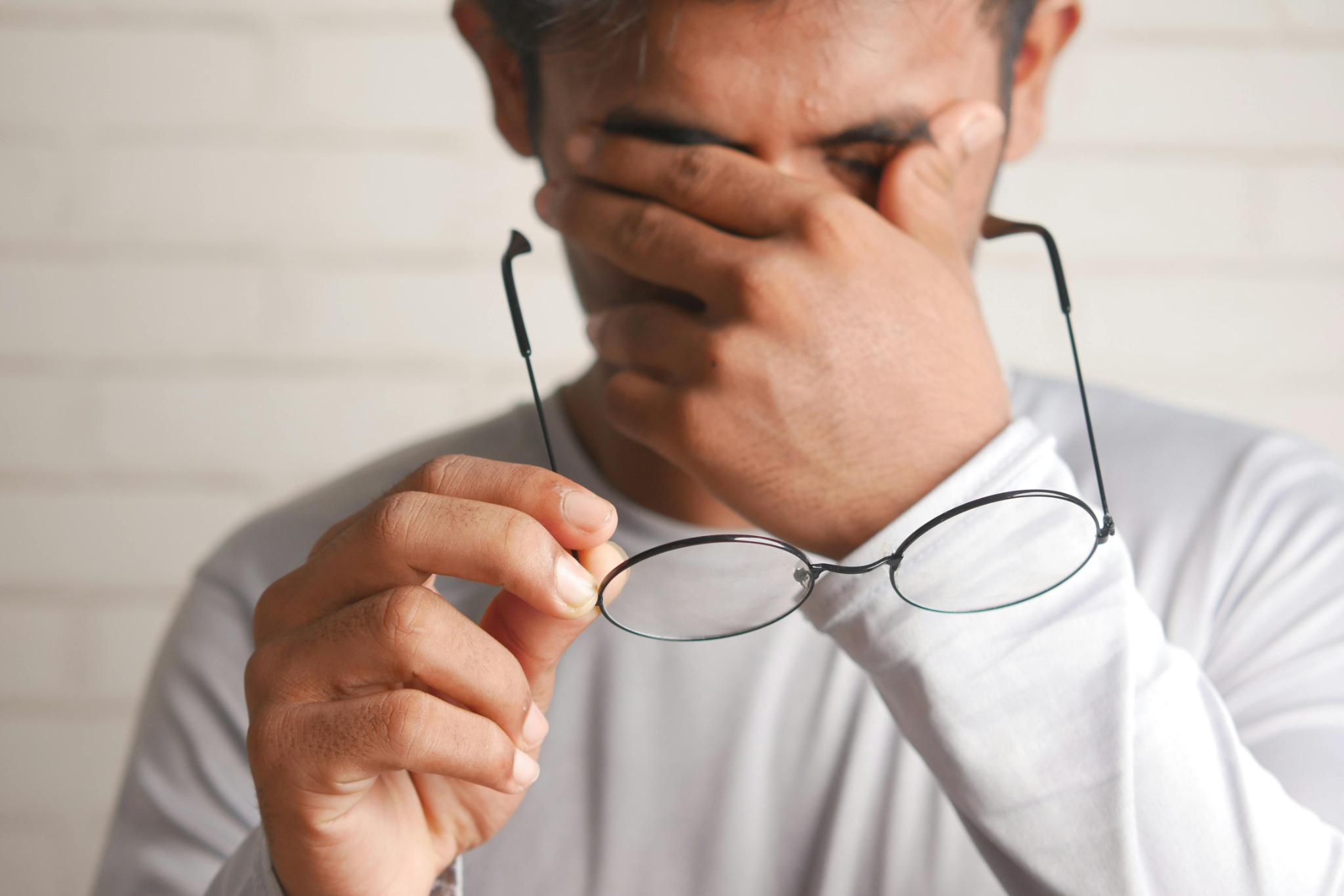 Man rubbing eyes holding glasses from digital eye strain