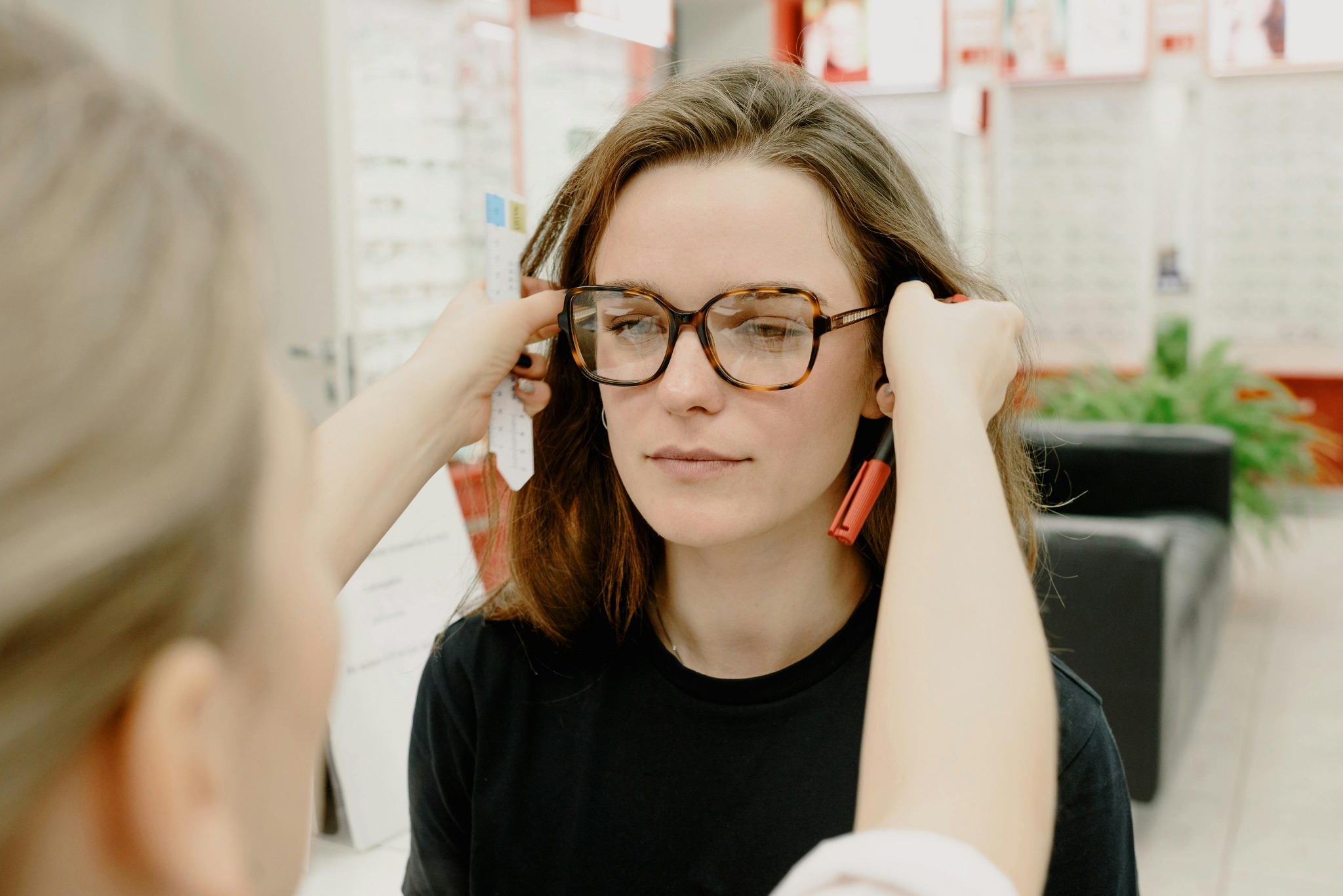 Optician adjusting glasses on a woman - face shape analysis